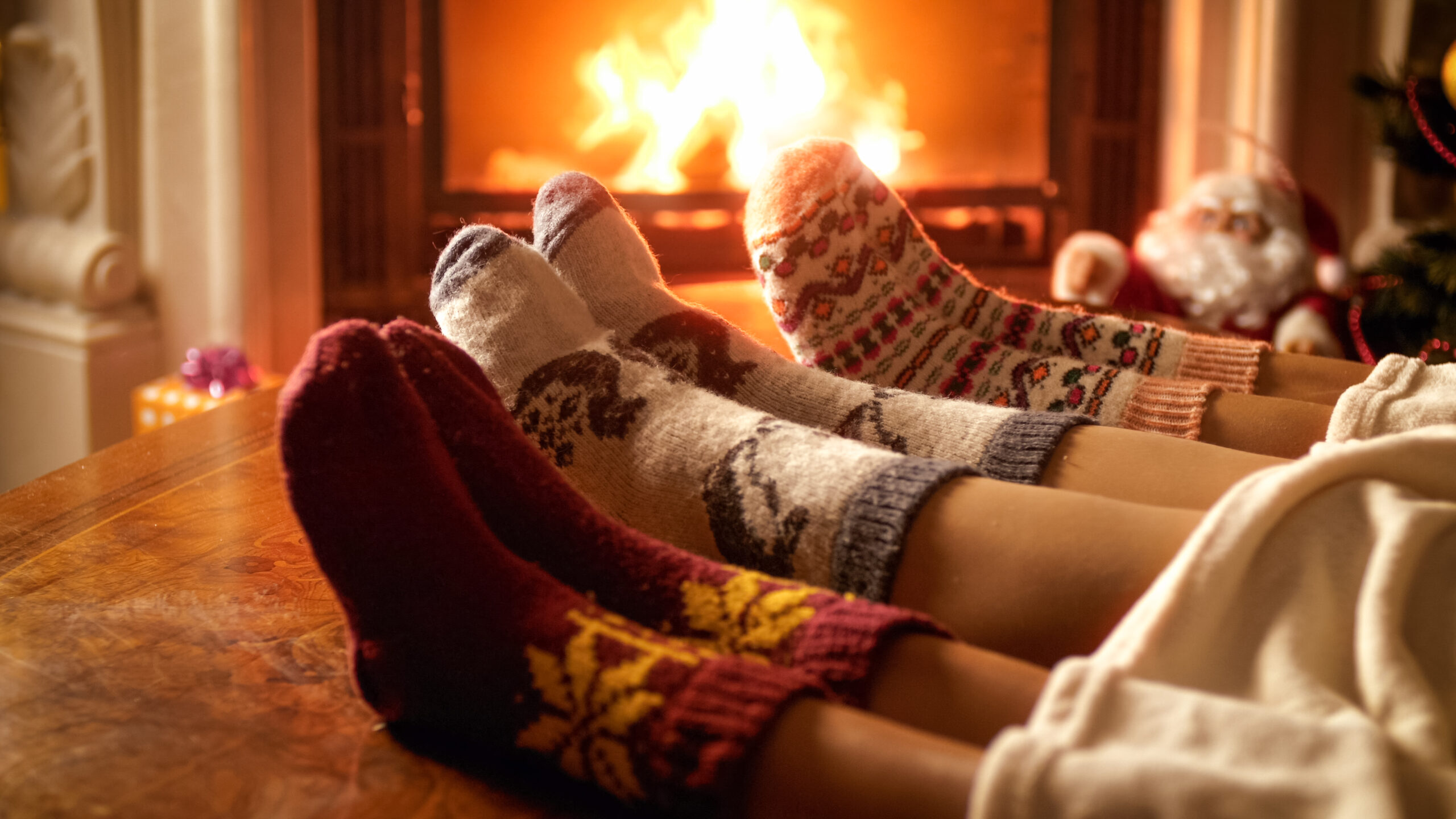 Closeup image of family feet in woolen socks lying next to fireplace